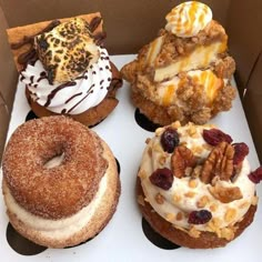 four different types of doughnuts in a box with nuts and other toppings