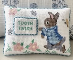 a cross stitch pillow with an embroidered peter rabbit on it