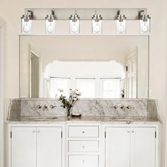 a bathroom vanity with two sinks and three lights above it in front of a mirror