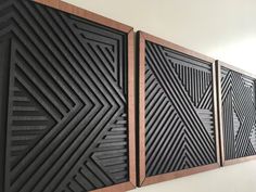 three black and brown art pieces hanging on the side of a wall in an office