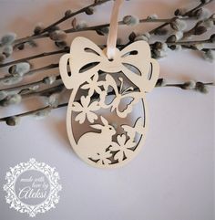 a wooden ornament hanging from a twig with flowers and rabbits on it