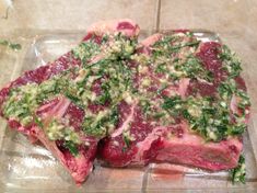 two pieces of raw meat sitting on top of a glass plate covered in green stuff