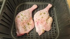 two pieces of raw chicken sitting on top of a black tray