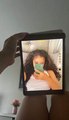 a person holding up a tablet with an image of a woman's face on it