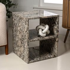 a marble side table with a knot on it's shelf next to a chair