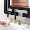 a person holding a glass in front of a sink with soap and toothbrushes