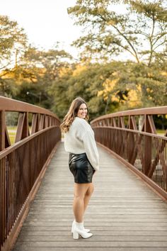 a woman standing on a bridge with her legs crossed