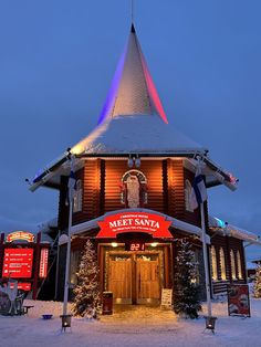 a building with a clock on the front and side of it covered in snow at night