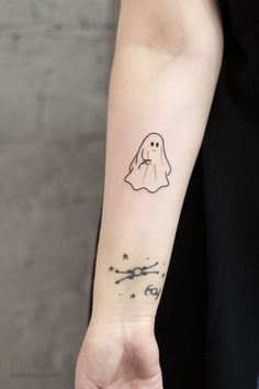 a person with a tattoo on their arm holding a scissors and a ghost in the background