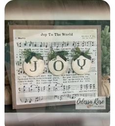 two white ornaments are sitting on top of a sheet of music paper with the words joy to the world