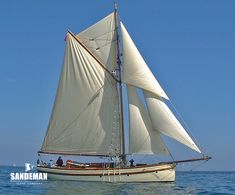 a sailboat with white sails is in the open water on a sunny day,