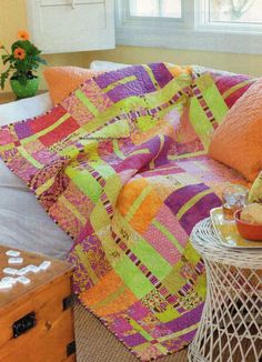 a living room with a couch covered in colorful quilts and pillows next to a window