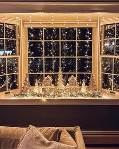 a living room filled with lots of christmas decorations next to a window covered in lights