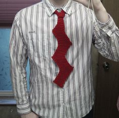 a man wearing a red tie and holding a cell phone up to his face while standing in front of a door