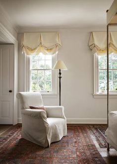 a white chair sitting on top of a rug next to a window