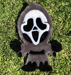 a black and white stuffed animal with a creepy face on it's back laying in the grass