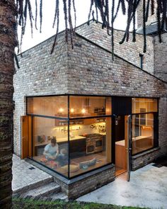 a person sitting in front of a brick building with glass walls and windows on the outside