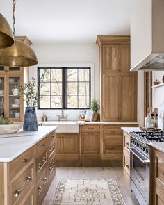 a large kitchen with wooden cabinets and white counter tops, an area rug on the floor