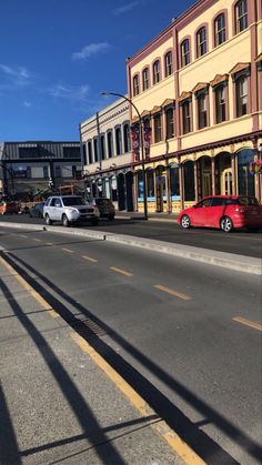 cars are parked on the side of an empty street in front of buildings and shops