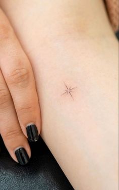 a small star tattoo on the back of a woman's left arm