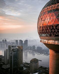 an aerial view of a city with tall buildings and water in the background at sunset