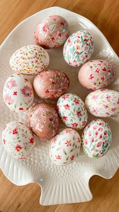 a white plate topped with decorated eggs on top of a wooden table