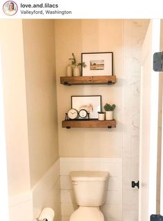 a white toilet sitting in a bathroom next to a wooden shelf filled with pictures and plants