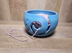 a blue bowl sitting on top of a wooden table next to a yarn ball and string