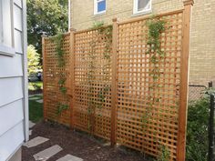 a wooden trellis next to a house in front of a brick wall and door