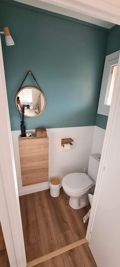 a white toilet sitting in a bathroom next to a wooden cabinet and mirror on the wall