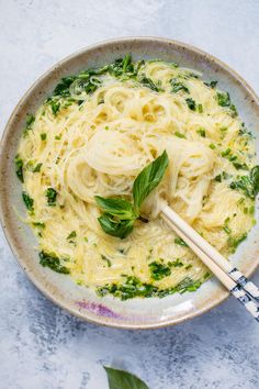 a white bowl filled with pasta and spinach