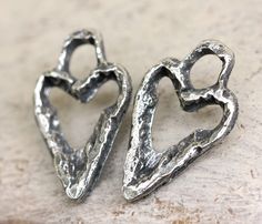 two silver heart shaped charms sitting on top of a table