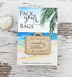 save the date card with luggage and seashell on white wood planks next to sea shell