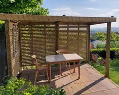 a table and chairs on a patio next to a pergolated area with trees