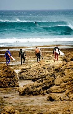 several surfers are walking on the beach with their surfboards