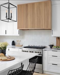 a kitchen with white cabinets and an island that has a cutting board on top of it