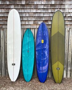 four surfboards lined up against a wooden fence