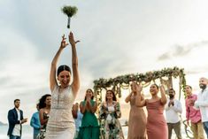 a group of people standing on top of a beach next to each other holding flowers