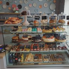 a display case filled with lots of different types of cakes and pastries on top of glass shelves