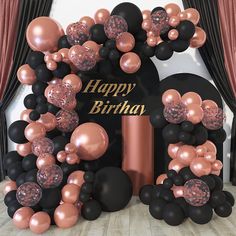 a happy birthday balloon arch with black and rose gold balloons