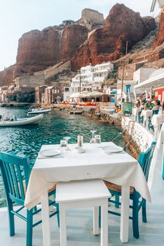 tables and chairs are set up on the dock in front of an island with boats