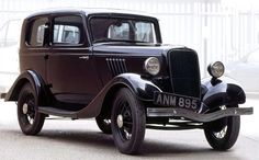 an old black car is parked in a garage