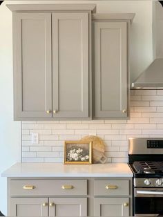 a kitchen with gray cabinets and white tile backsplashes, an oven and microwave