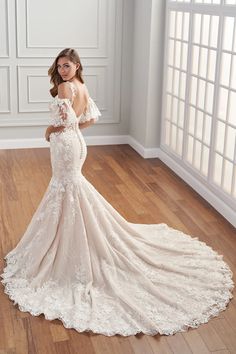 a woman in a wedding dress standing on the floor with her back to the camera