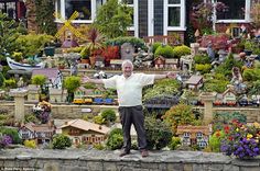 a man standing on top of a stone wall next to a garden filled with lots of plants