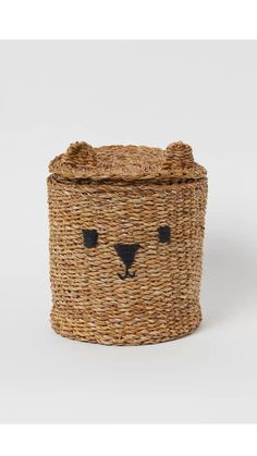 a woven basket with a bear face on the front and black eyes painted on it