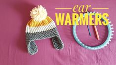 a knitted hat sitting on top of a table next to a knitting needle and an ear warmer