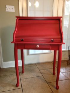 a red piano sitting on top of a tile floor next to a door and window