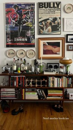 there are many pictures on the wall above this bookshelf and below it is a bookcase with various books