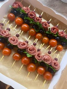 an arrangement of food on sticks with tomatoes and olives